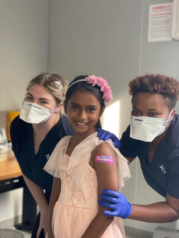 A child standing between two nurses who has just been vaccinated