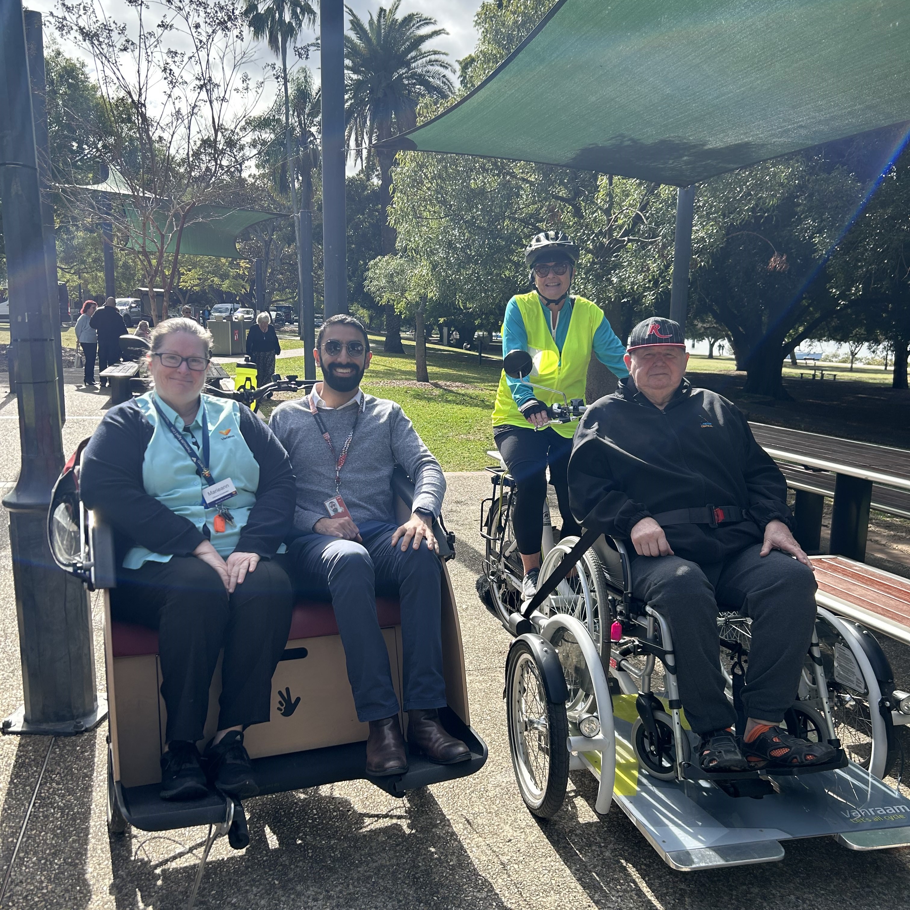 three people sitting in the front of the cycling without age bicycles, with one volunteer ready to peddle