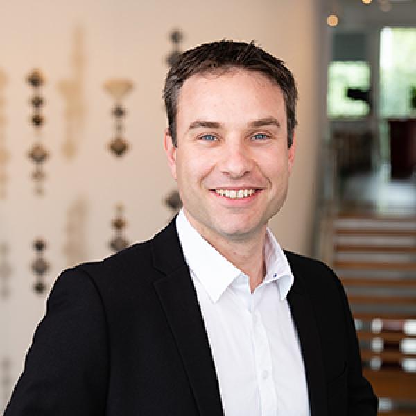 Man in black suit and white shirt smiling at camera